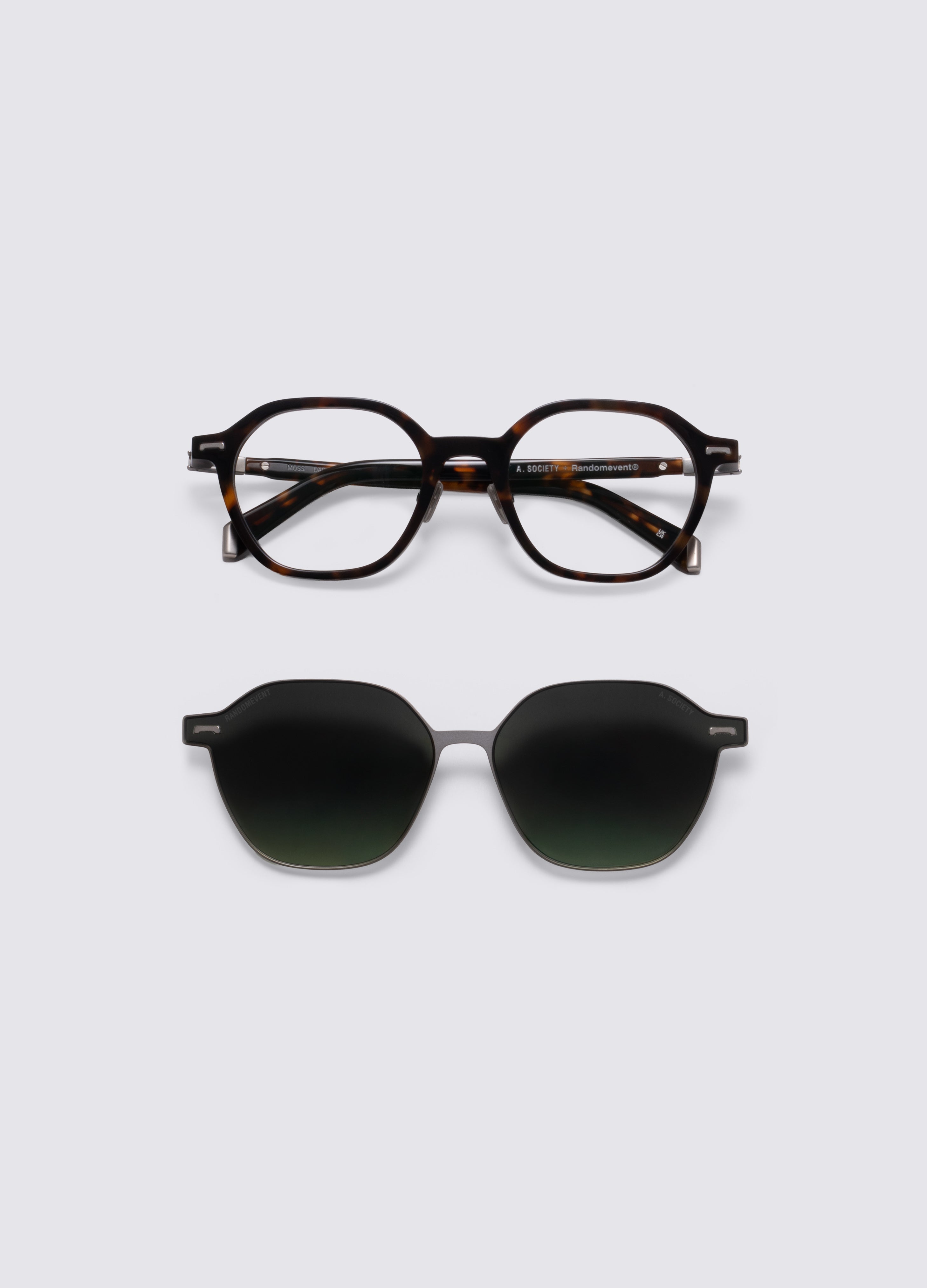 Close-up of a pair of glasses with a tortoiseshell acetate frame and dark green gradient clip-on lenses, shown on a light gray background. #Dark Havana Silver