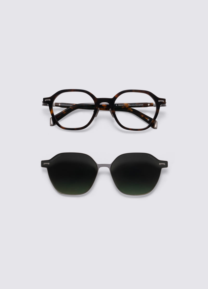 Close-up of a pair of glasses with a tortoiseshell acetate frame and dark green gradient clip-on lenses, shown on a light gray background. #Dark Havana Silver