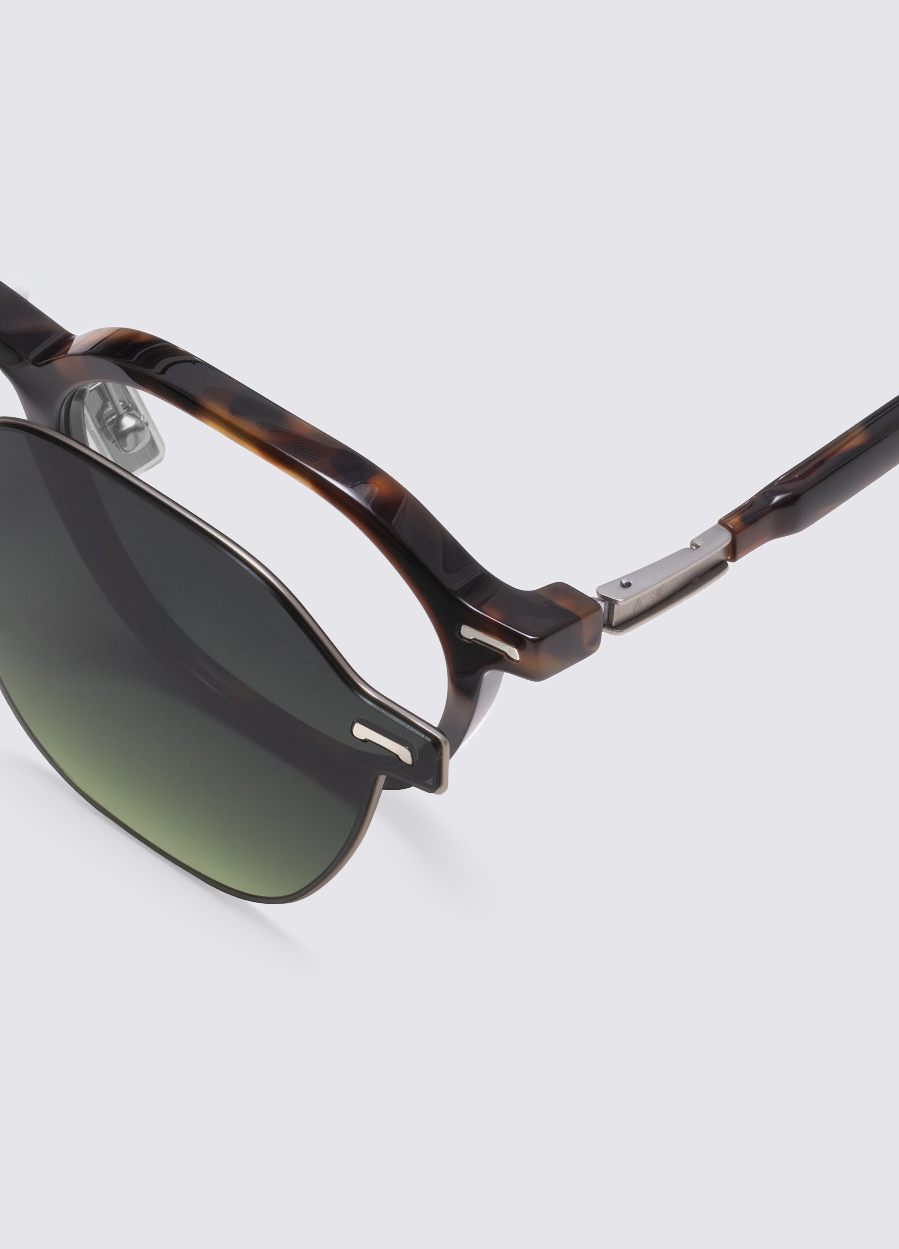 Close-up of a pair of sunglasses with a tortoiseshell acetate frame and dark green gradient lenses, shown on a light gray background. #Dark Havana Silver